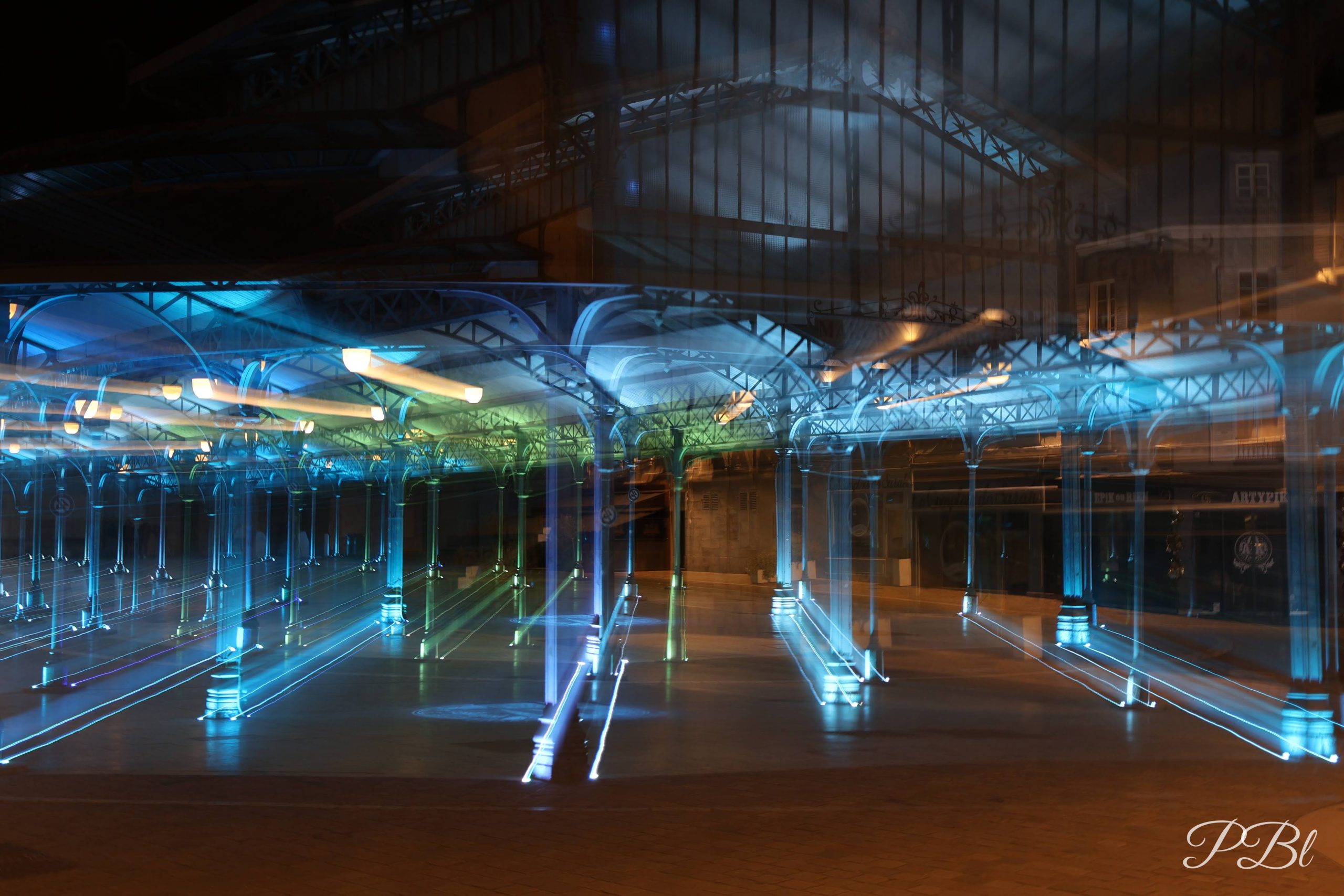 Halle illuminée en pose longue, traînées de lumière bleue