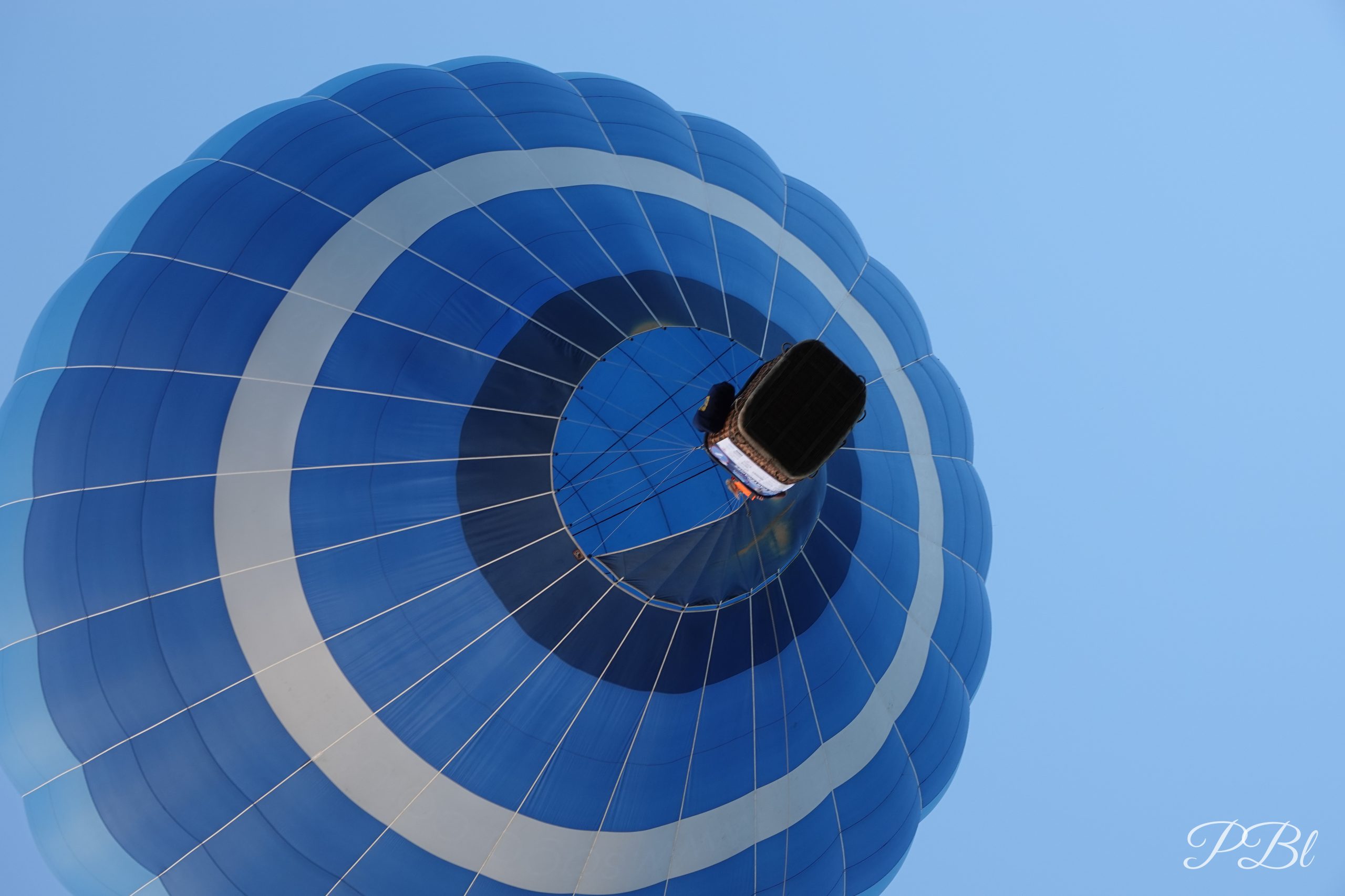 Montgolfière bleue et blanche vue de dessous, dans le ciel
