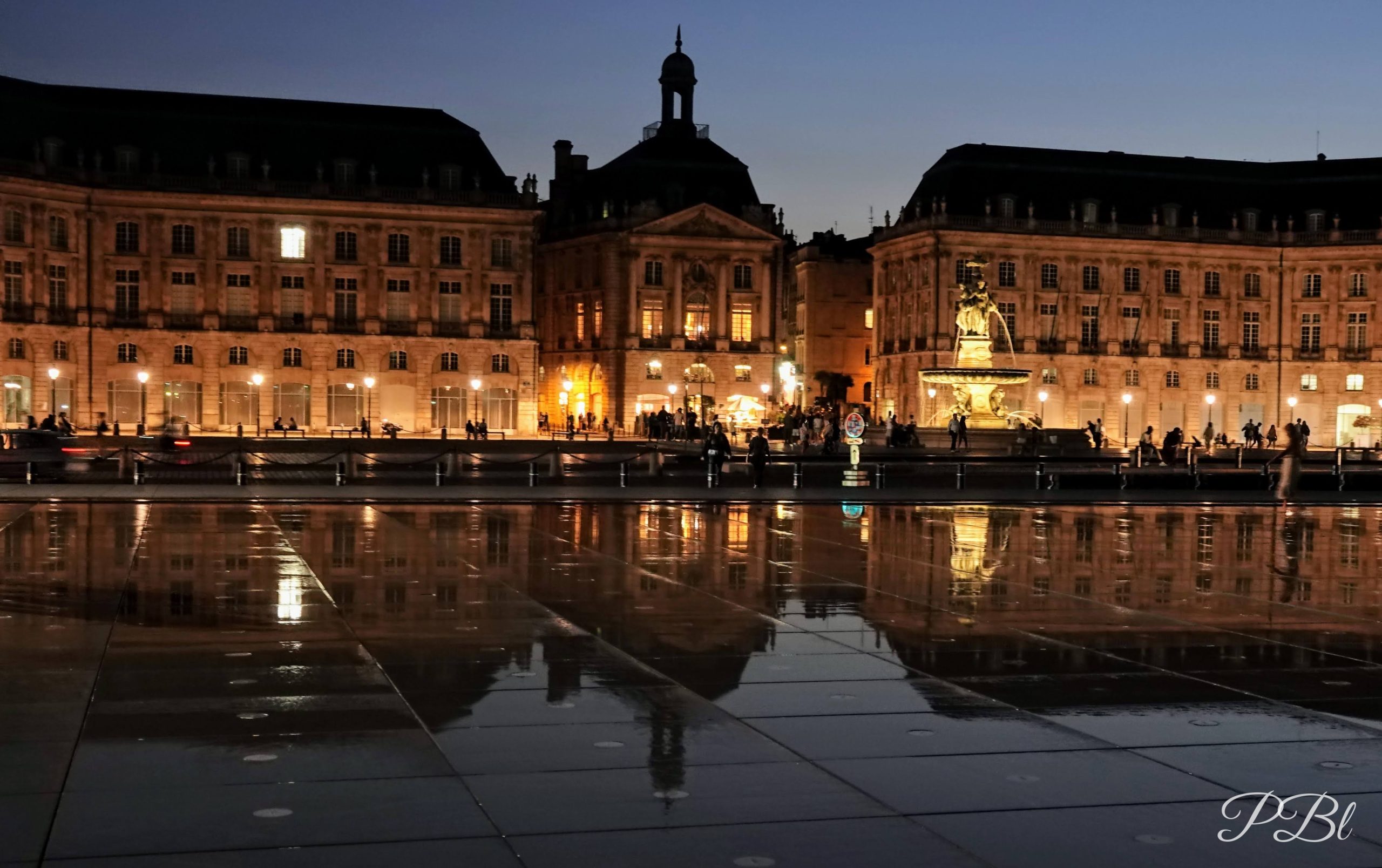 Place illuminée la nuit et son reflet sur un miroir d'eau