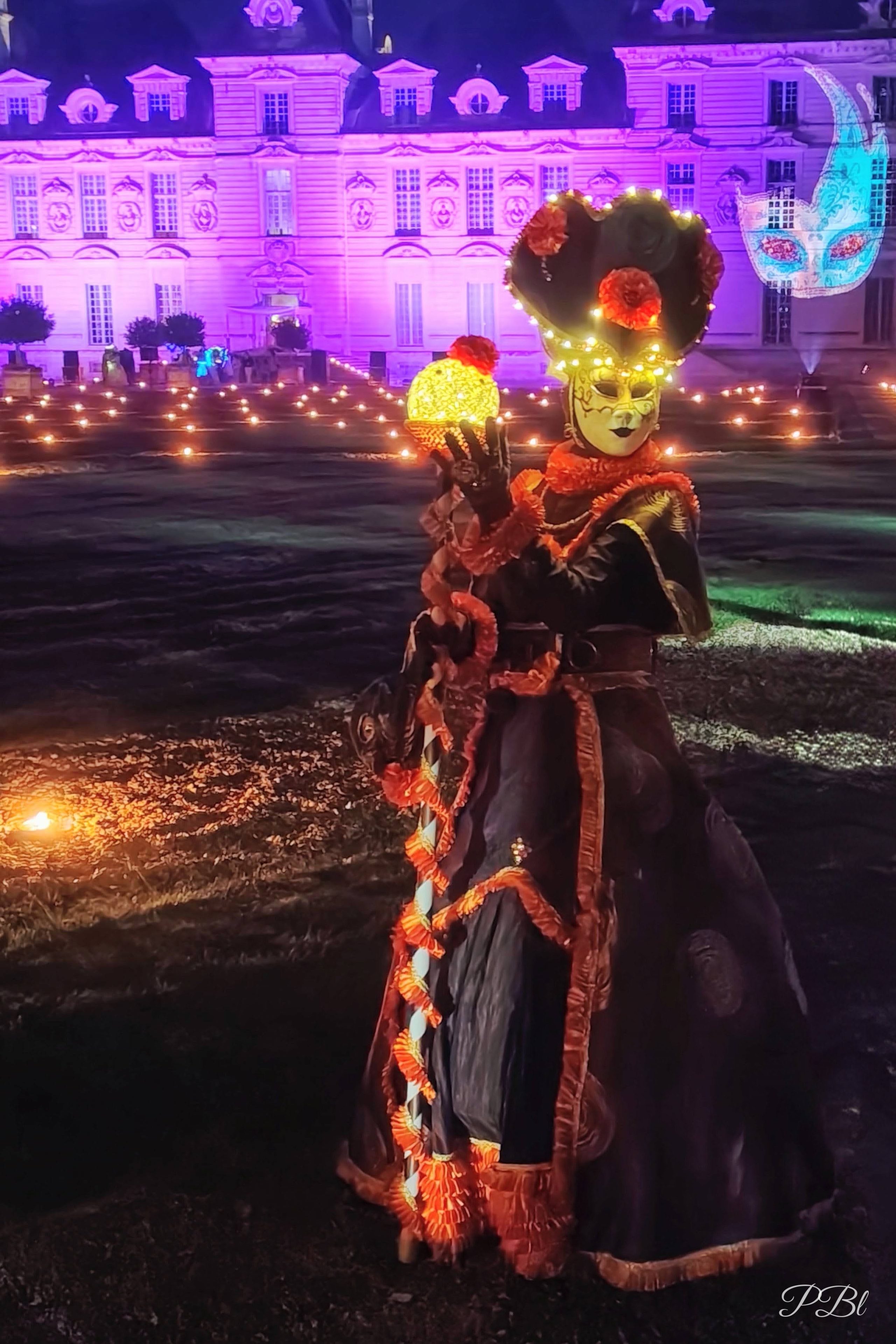 Costume de carnaval lumineux devant un château éclairé de violet, la nuit