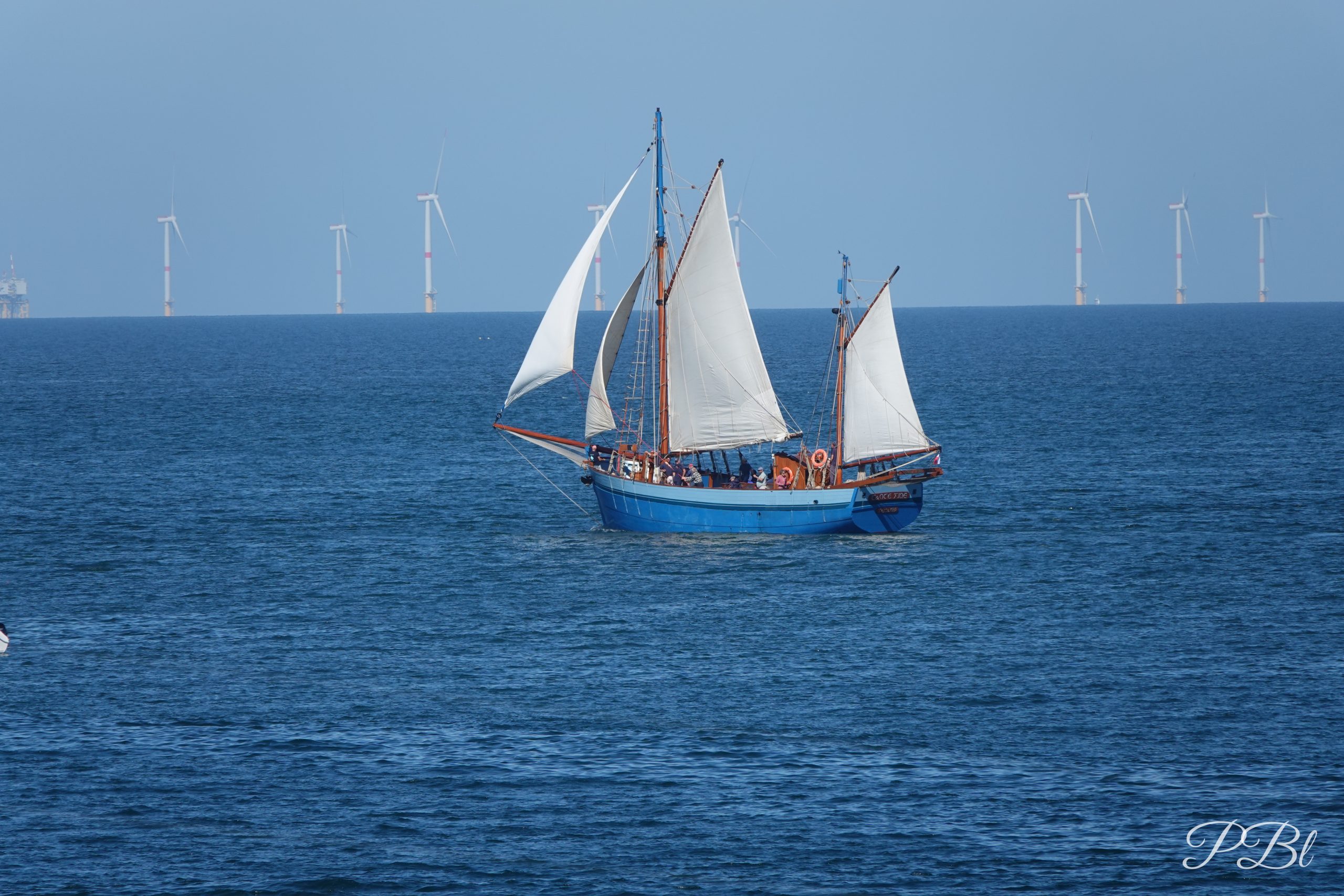 Vieux gréement toutes voiles dehors, éoliennes à l'horizon