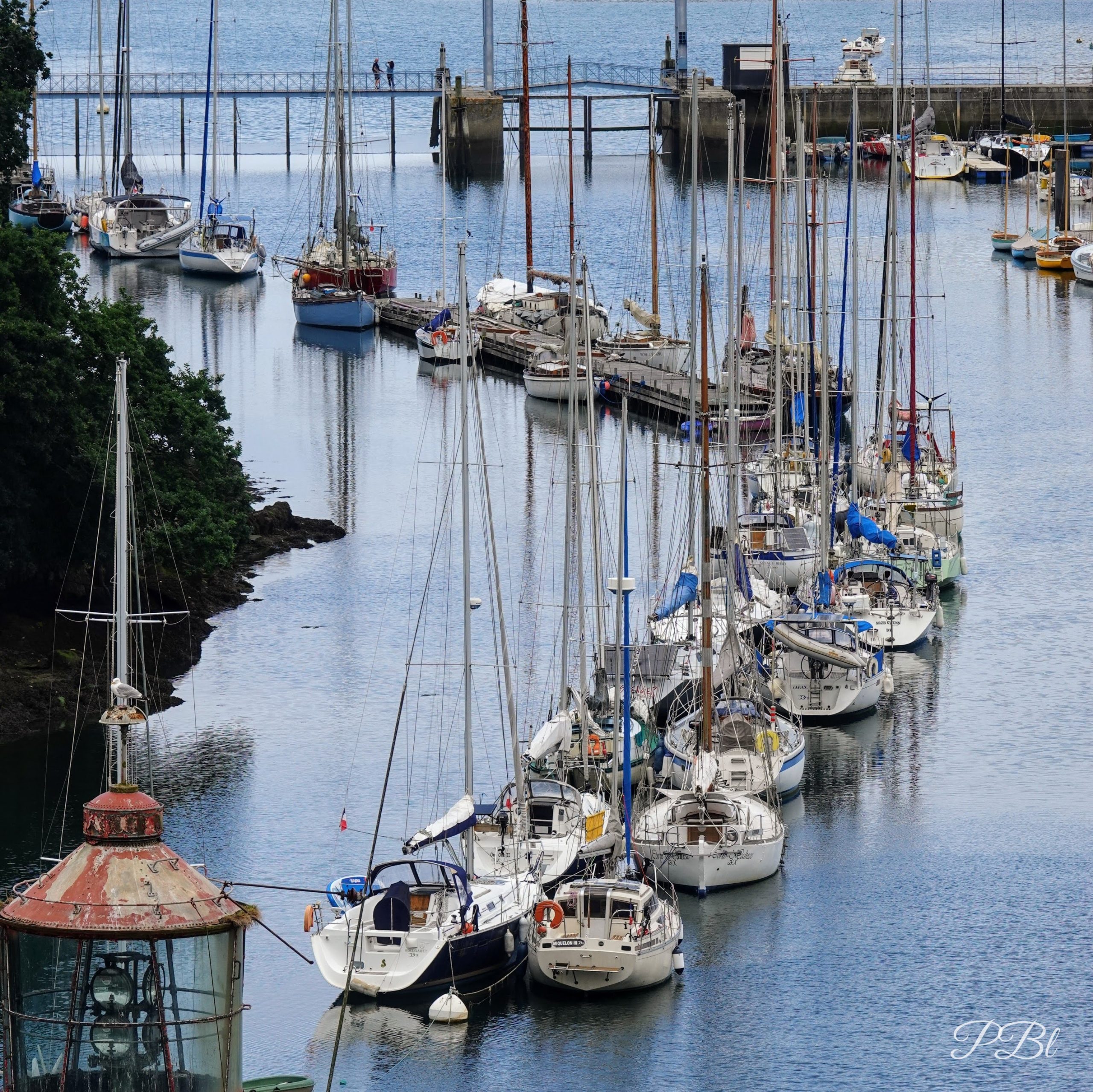 Voiliers amarrés dans un port, un petit phare au premier plan