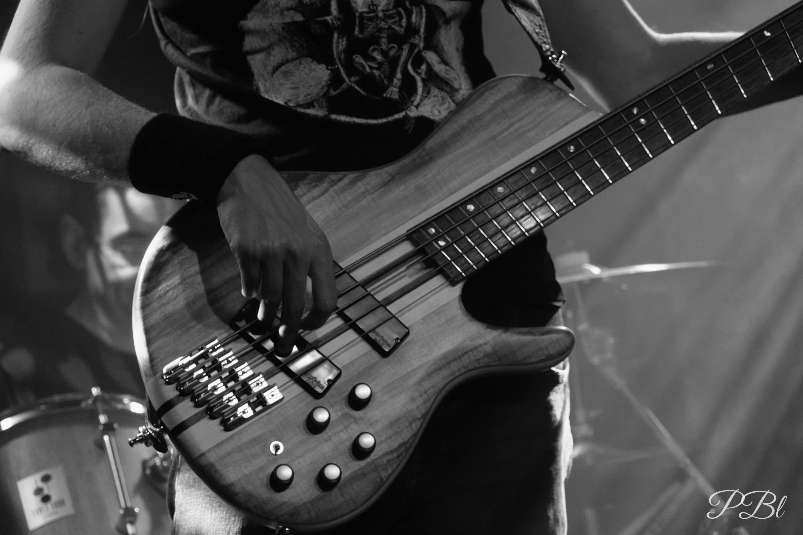 Main d'un musicien sur une guitare basse, en noir et blanc