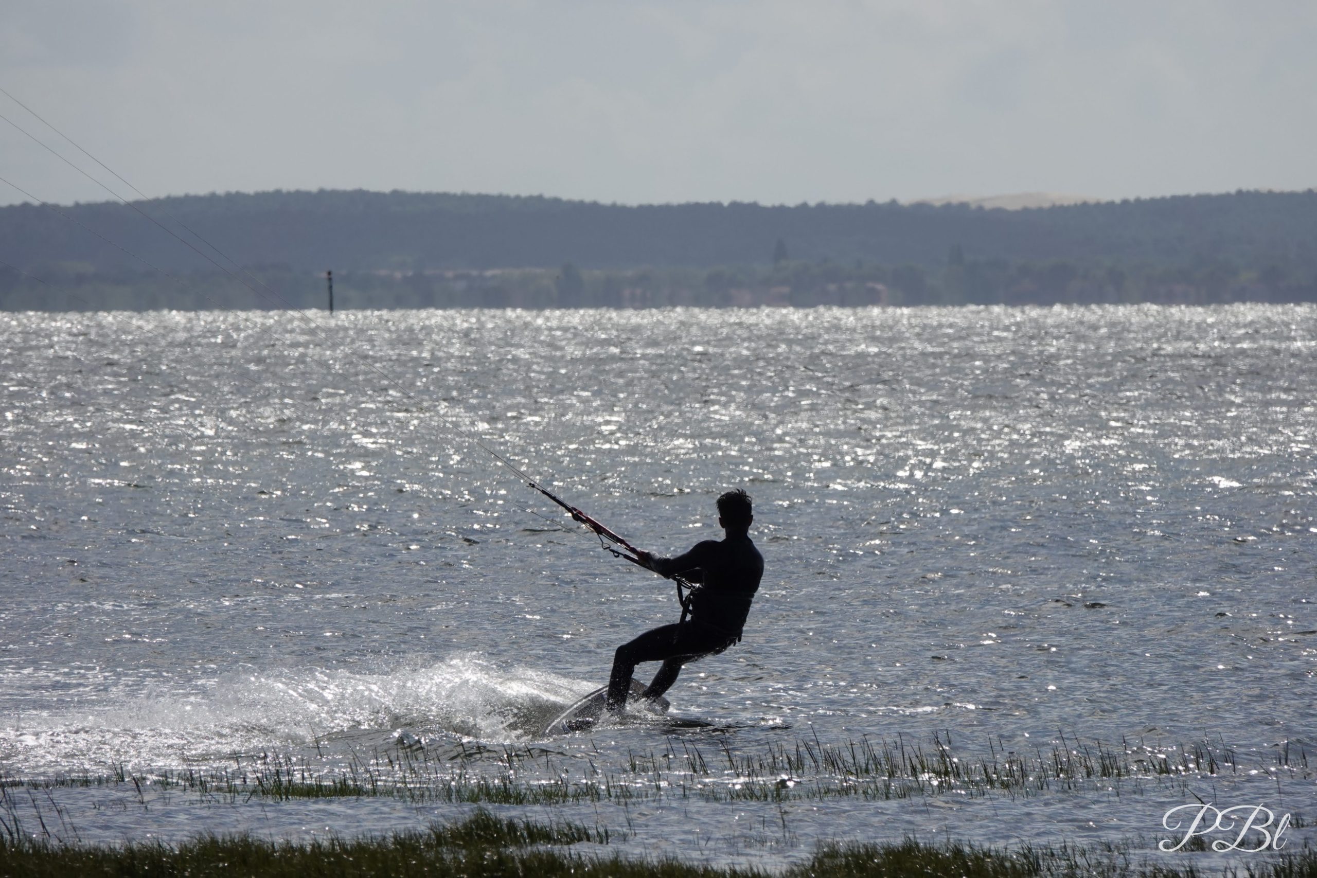 Kitesurfeur en silhouette sur une eau scintillante