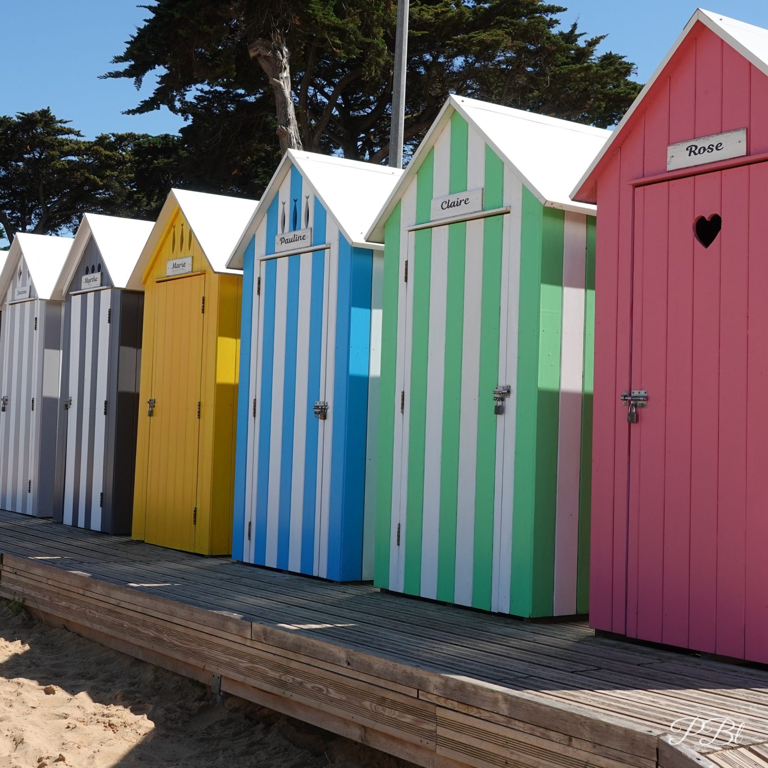 Cabines de plage colorées à rayures, alignées sur le sable