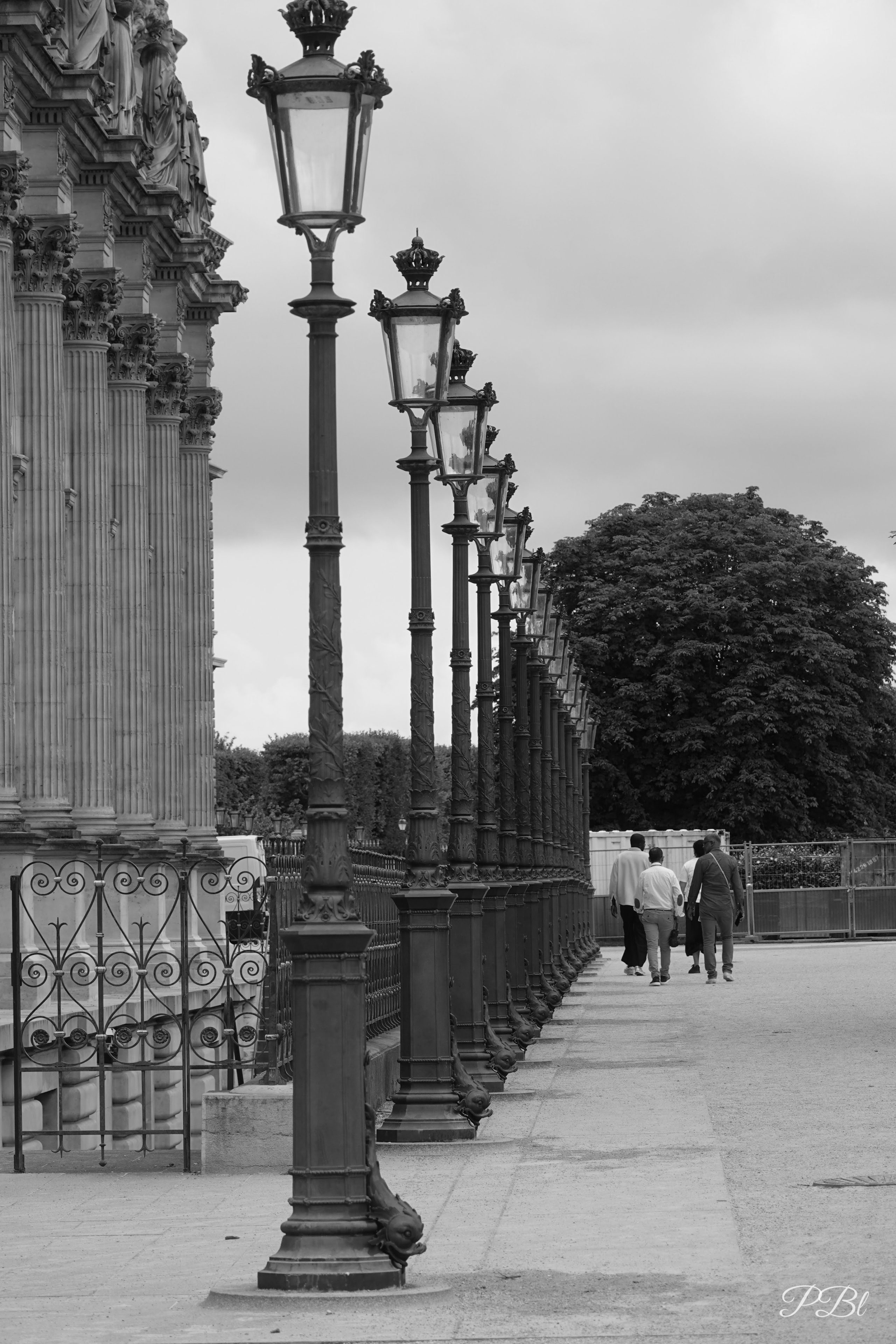 Alignement de réverbères le long d'un palais, en noir et blanc
