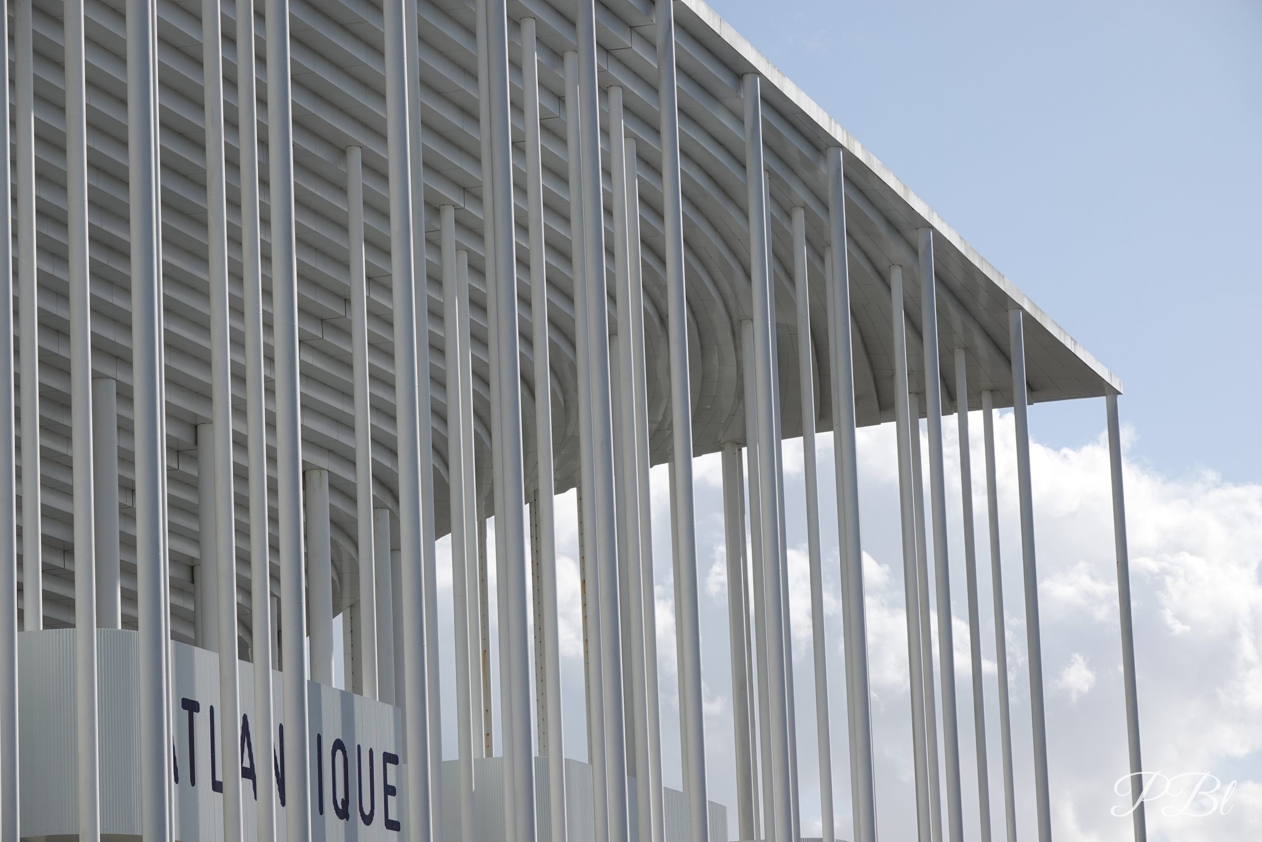 Façade blanche aux fines colonnes d'un stade moderne, inscription « Atlantique »